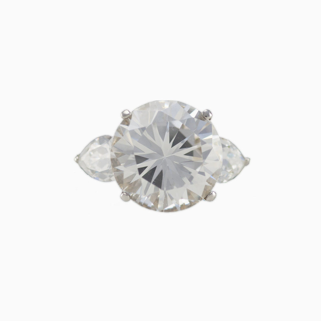 Sterling silver, rhodium plated, large round brilliant cut cubic zirconia ring with pear cubic zirconia shoulders.